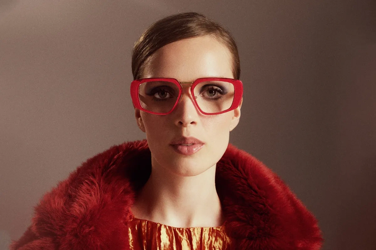 The pink eyewear model Cassoipeja, worn by a woman in a read faux fur coat